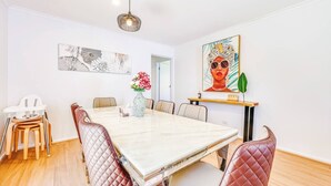 A dining area with a marble table, cushioned chairs, a vase with flowers, and artwork on the walls.