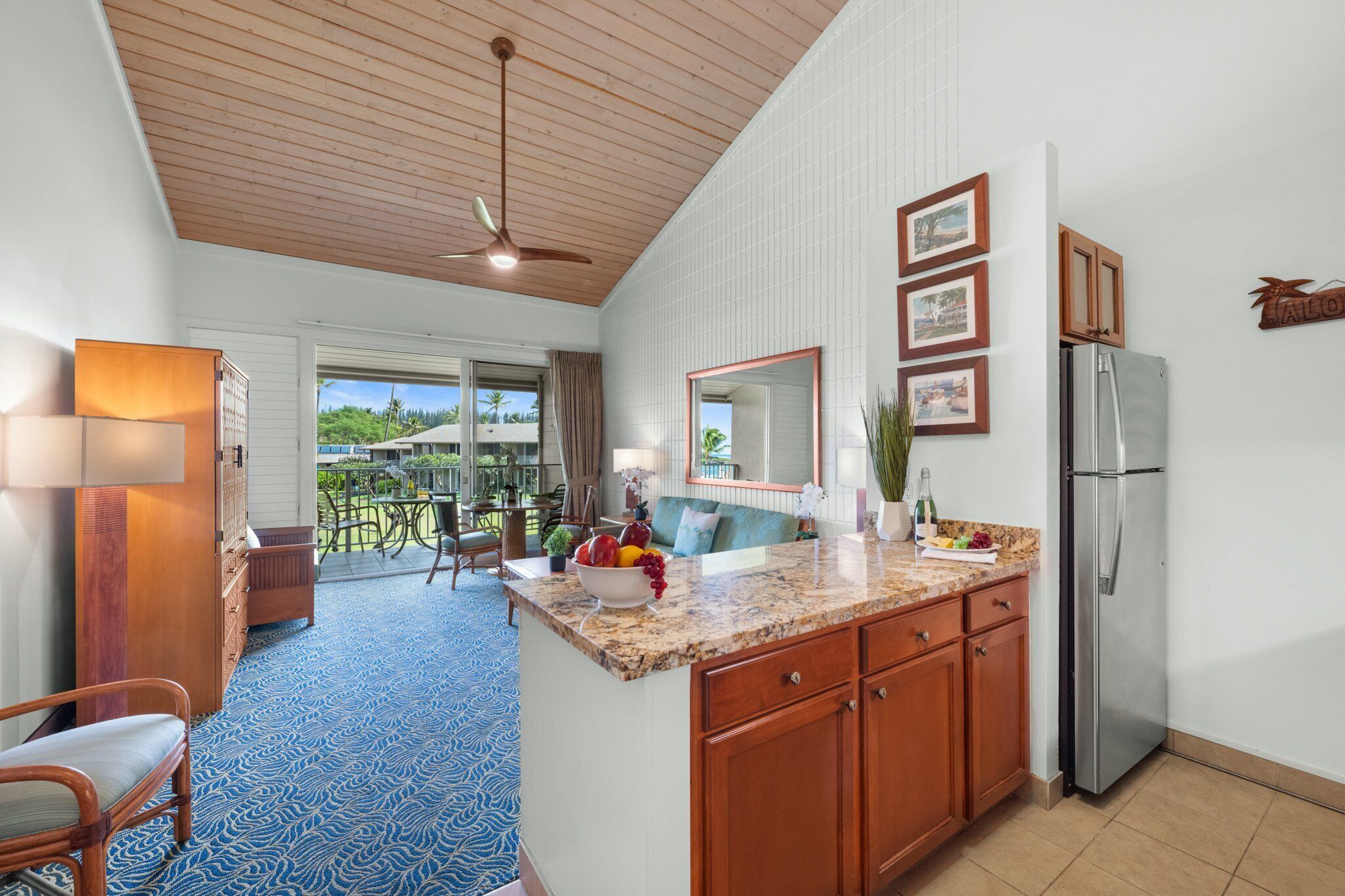 A kitchen with a granite countertop, wooden cabinets, and a stainless steel refrigerator.