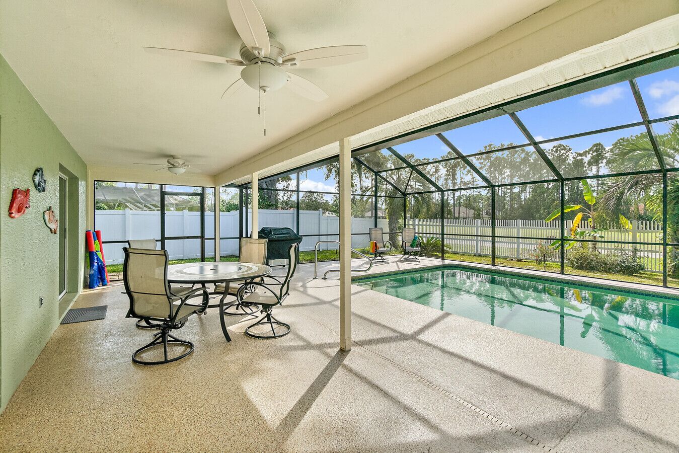 A covered patio area with a pool, outdoor seating, and a view of a lake.