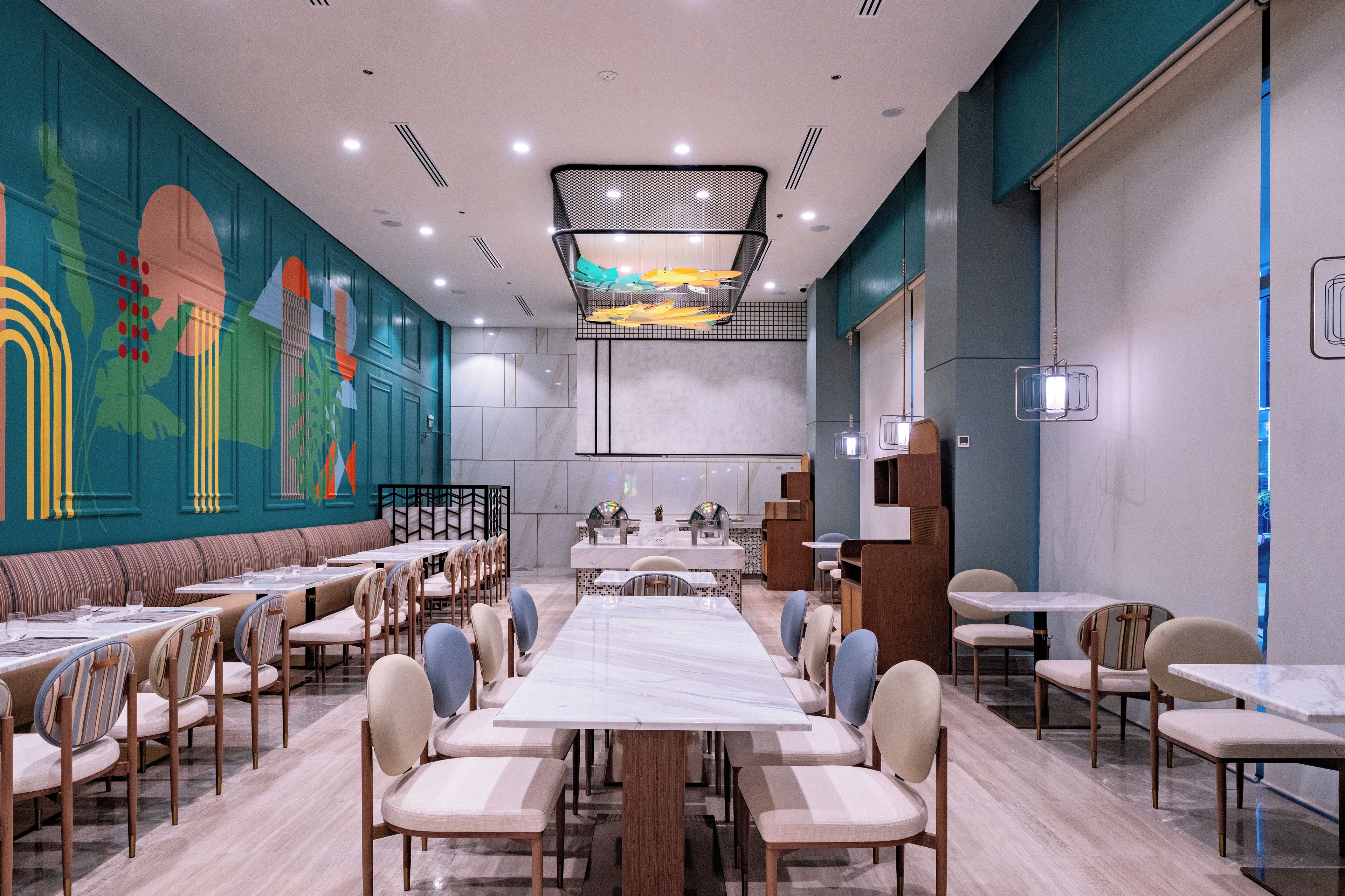 Ein Restaurant mit einem langen Gemeinschaftstisch, einzelnen Tischen und Stühlen.