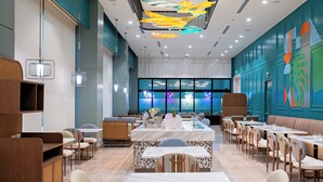 A modern restaurant with a central island, seating around it, and a colorful ceiling design. - Belmont Hotel Iloilo (Mandurriao)