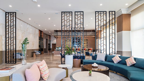 A modern lobby with seating areas, a reception desk, and decorative panels. - Belmont Hotel Iloilo (Mandurriao)