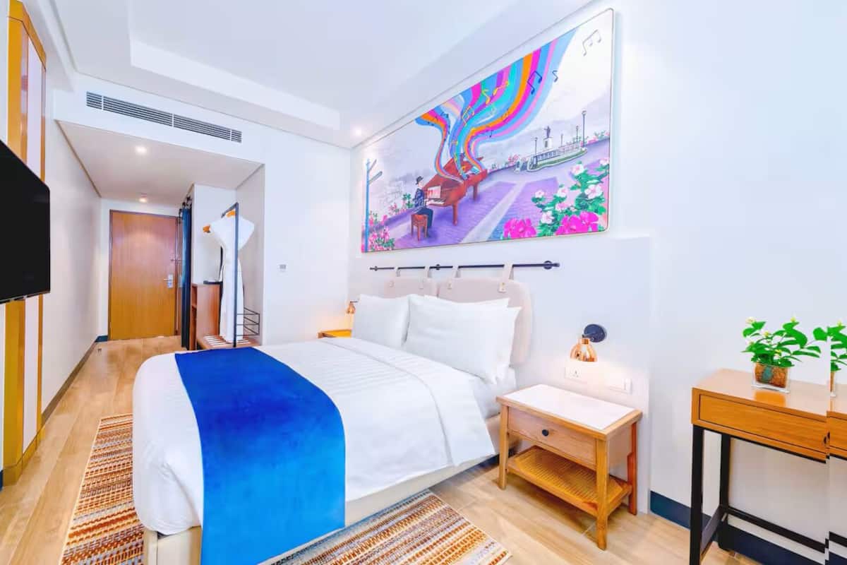 Una camera d'albergo con un letto, comodino e un'ampia parete decorata con un murale.