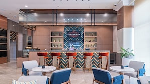 A modern bar area with a central bar, seating, and a decorative wall with shelves. - Belmont Hotel Iloilo (Mandurriao)