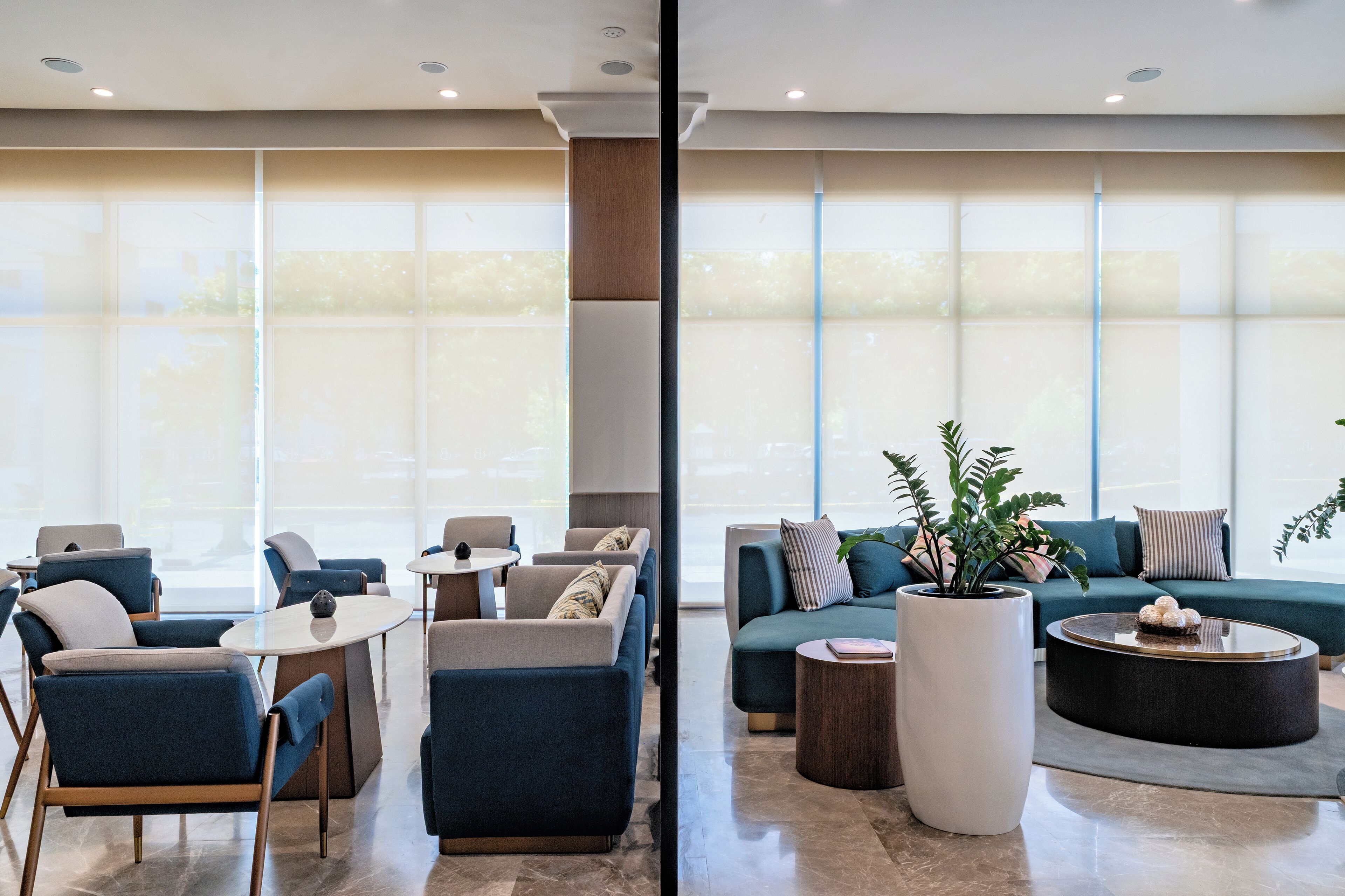 A modern hotel lobby with seating areas, large windows, and a central column.