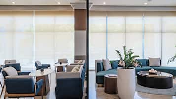 A modern hotel lobby with seating areas, large windows, and a central column.