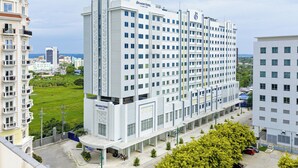 A multi-story hotel with a modern design, featuring a central courtyard and a parking area. - Belmont Hotel Iloilo (Mandurriao)