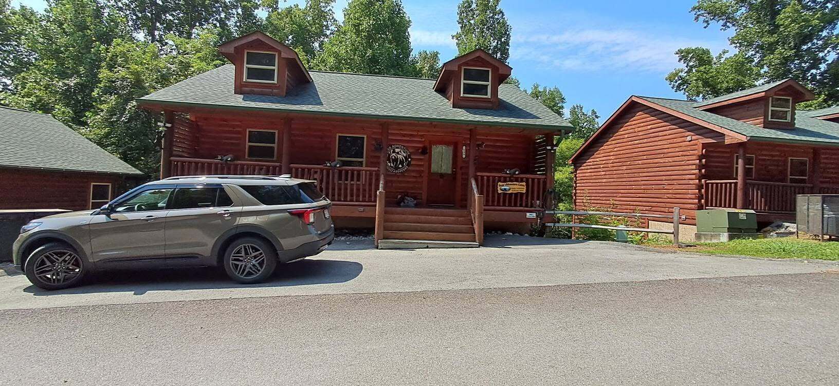 Una baita con un portico, un'auto parcheggiata davanti e un cartello che indica un ristorante.