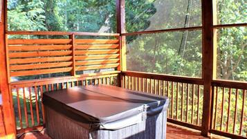 Un espace extérieur abrité, doté d’une table et de bancs, entouré de rampes en bois et de grandes fenêtres.