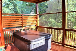 Un espacio al aire libre cubierto con mesas y bancos, rodeado de barandales de madera y grandes ventanales.
