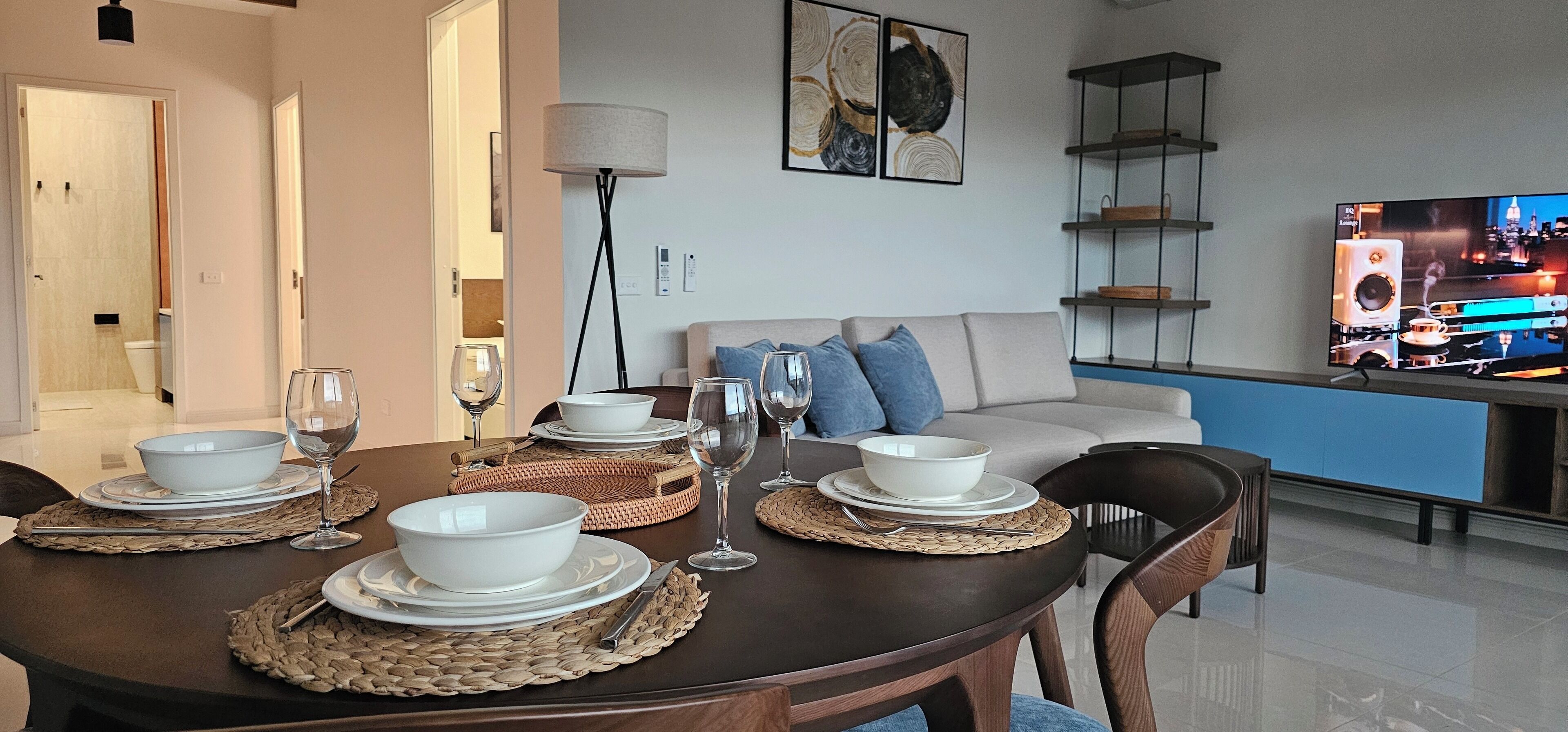 Un comedor con una mesa redonda para cuatro personas, un sofá y un televisor al fondo.