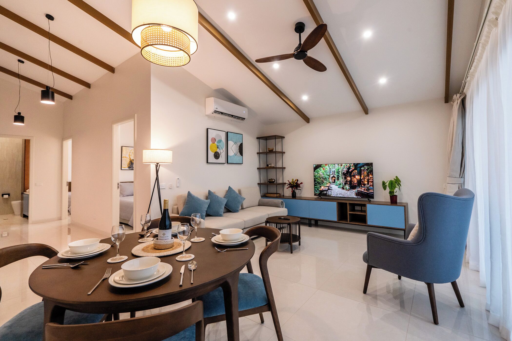 A modern living room with a dining area, a ceiling fan, and a TV.
