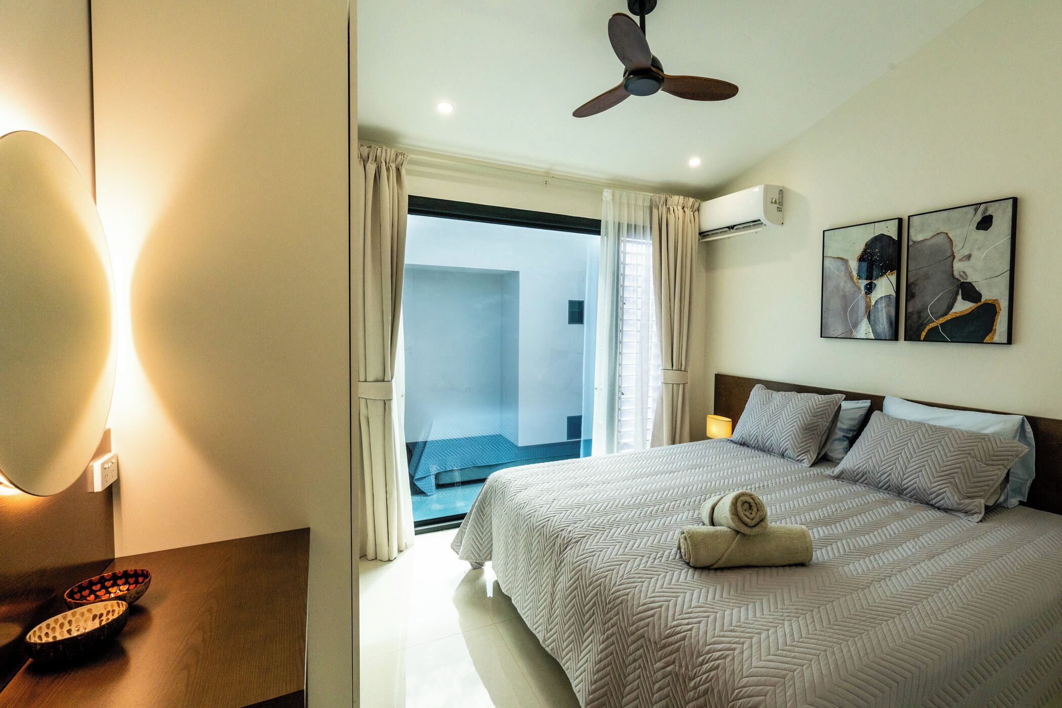 A hotel room with a bed, a ceiling fan, a window with curtains, and a wall-mounted air conditioner.