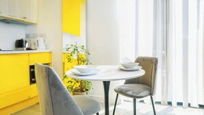 A bright yellow kitchen with a white dining table and two chairs. - Chic Studio | Prime Location | Free Parking (Sheffield)