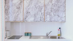 A kitchen with marble cabinets, a stainless steel sink, a toaster, and two teal containers. - Comfy Studio Apartment in Heart of Sheffield (Sheffield)