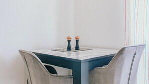 A small dining table with two salt and pepper shakers, two chairs, and a striped curtain in the background. - Comfy Studio Apartment in Heart of Sheffield (Sheffield)