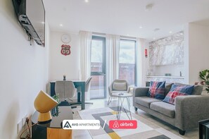 A modern apartment with a dining area, a sofa, and a kitchen. - Comfy Studio Apartment in Heart of Sheffield (Sheffield)