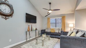 A living room with a sofa, a coffee table, a TV, and a ceiling fan.