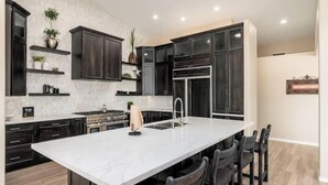 Una cocina moderna con armarios oscuros, una isla grande y electrodomésticos integrados.