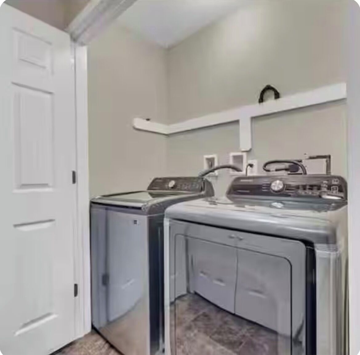 A laundry room with two front-loading washing machines and a dryer.
