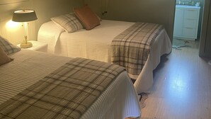 Makuuhuoneessa on kaksi sänkyä, kattotuuletin, yöpöytä lampun kanssa ja ikkuna, josta on näkymä vehreään maisemaan.