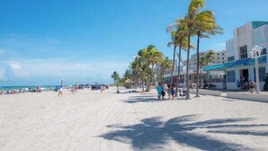 A beach with palm trees, a sandy shore, and buildings in the background. - Private Chic Studio with Patio • King Bed • Near Beach (Hollywood)