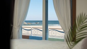 Una habitación con un ventanal grande con vistas a una playa y barandilla.