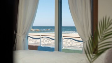 Una habitación con un ventanal grande con vistas a una playa y barandilla.