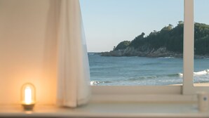 Una ventana con vista al mar y a una costa rocosa.