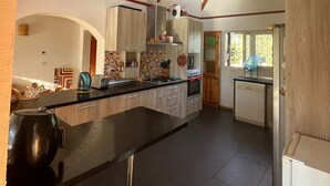 A modern kitchen with a central island, built-in appliances, and a view to the dining area. - CasaBosque minutes from the sea. (Placilla)