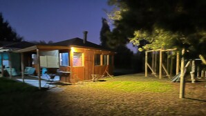 A wooden cabin with a porch, a swing set, and a small deck area. - CasaBosque minutes from the sea. (Placilla)
