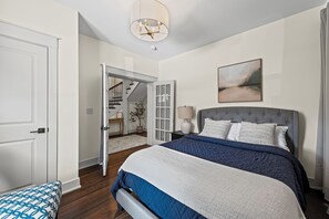 Ein Schlafzimmer mit einem großen Bett, einer Chandelüster, einer Treppe und einem Gemälde an der Wand.