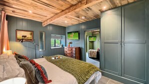 Ein Schlafzimmer mit einem Bett, einem Schminktisch, einem Fernseher und einem Kleiderschrank.