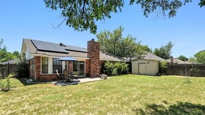 A residential backyard with a patio, a brick chimney, and a covered outdoor seating area. - The Gathering Place: Near Zoo/Park & Expo Center (Abilene)