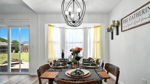 A dining area with a table set for four, a chandelier, and a sign on the wall. - The Gathering Place: Near Zoo/Park & Expo Center (Abilene)