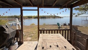 An outdoor deck with a view of a lake, a grill, and string lights. - Lakeside Hideaway 5-Min to Shackleford AI Site! (Abilene)