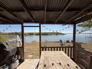 An outdoor deck with a view of a lake, a grill, and string lights. - Lakeside Hideaway 5-Min to Shackleford AI Site! (Abilene)