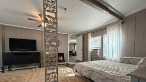 A bedroom with a bed, a television, a decorative partition, and a ceiling fan. - Lakeside Hideaway 5-Min to Shackleford AI Site! (Abilene)