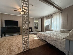 A bedroom with a bed, a television, a decorative partition, and a ceiling fan. - Lakeside Hideaway 5-Min to Shackleford AI Site! (Abilene)