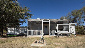 A single-story house with a front porch, a covered outdoor area, and a small garden. - Lakeside Hideaway 5-Min to Shackleford AI Site! (Abilene)