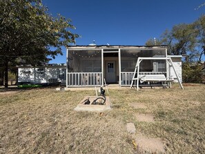 A single-story house with a front porch, a covered outdoor area, and a small garden. - Lakeside Hideaway 5-Min to Shackleford AI Site! (Abilene)