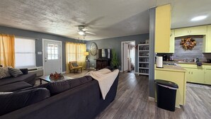 A living room with a sofa, a coffee table, and a television. There is a kitchen area with cabinets and a sink. - Lakeside Hideaway 5-Min to Shackleford AI Site! (Abilene)