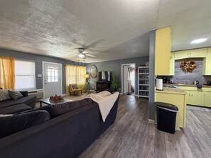 A living room with a sofa, a coffee table, and a television. There is a kitchen area with cabinets and a sink. - Lakeside Hideaway 5-Min to Shackleford AI Site! (Abilene)