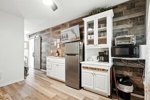 Une cuisine moderne avec des meubles blancs, un réfrigérateur en acier inoxydable, un four à micro-ondes et un panneau indiquant qu’il s’agit d’un établissement proposant des chambres d’hôtes.
