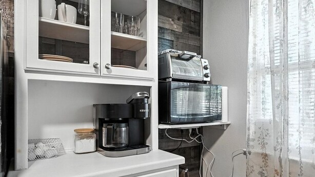 A kitchen with a coffee maker, a toaster, and a microwave on a white countertop. - Mockingbird Lane – Cozy Rustic Retreat (Abilene)