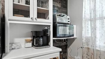 Una cocina con cafetera, tostadora y microondas sobre una encimera blanca.