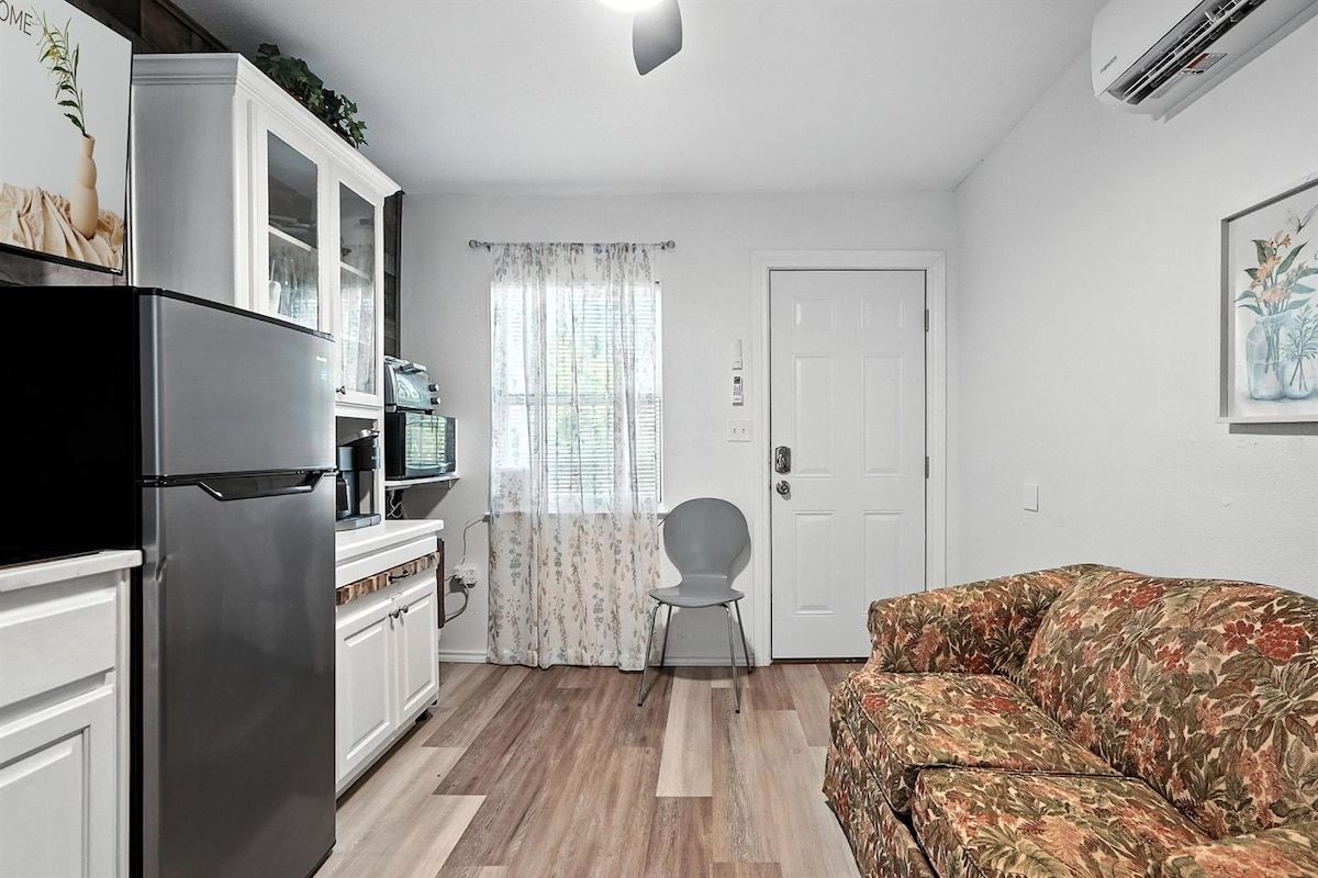 A compact living space with a kitchenette, a sofa, and a door.