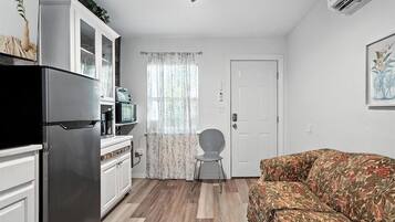 A compact living space with a kitchenette, a sofa, and a door.