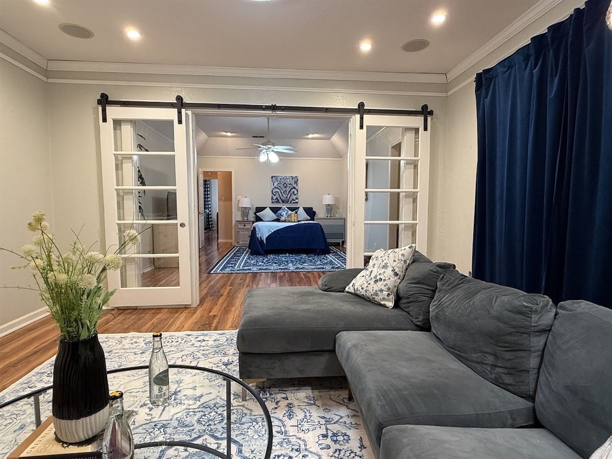 A modern living room with a grey sectional sofa, a coffee table, and a blue patterned rug.