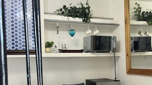 Una cucina compatta con tavolo e sedie, un frigorifero e un forno a microonde.